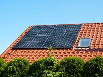 New solar panels on the red tin roof of a private house background. Renewable green energy abstract.